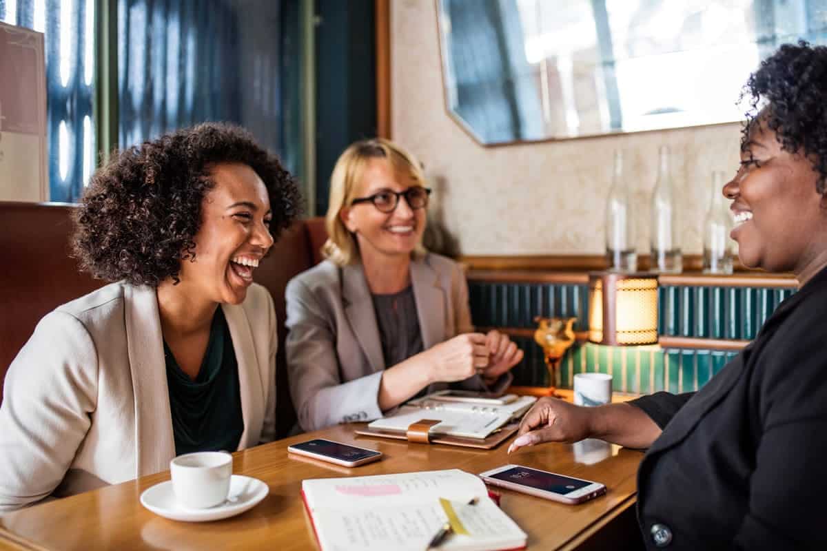 Women laughing during a meeting at a cafe.