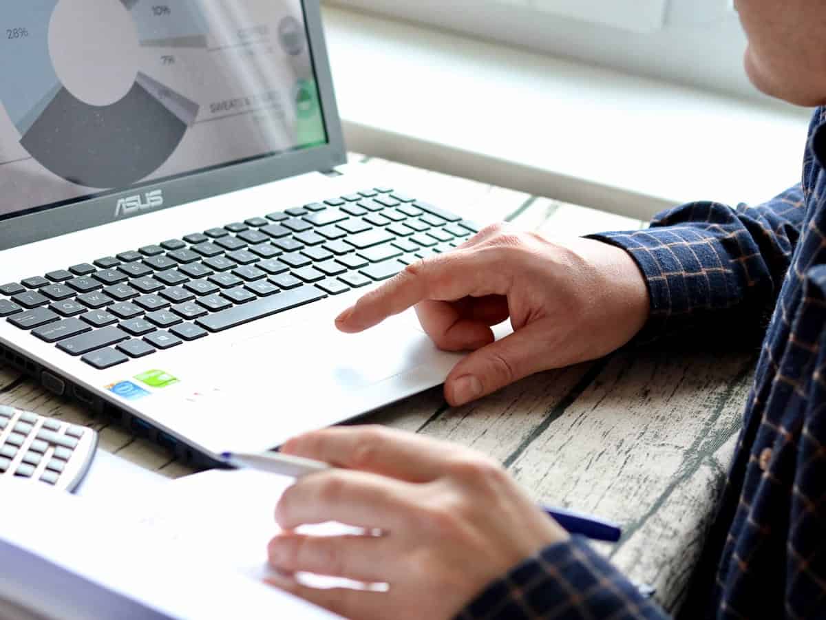 A photo of a man working on a laptop in his office.