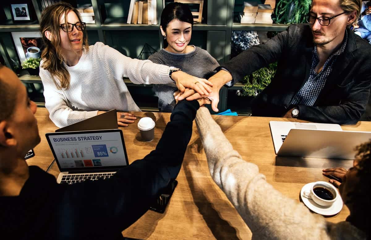 Team putting their hands in for a cheer after a meeting.