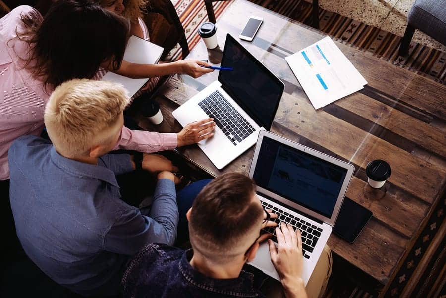 A photo of a design team looking at various designs on laptops.