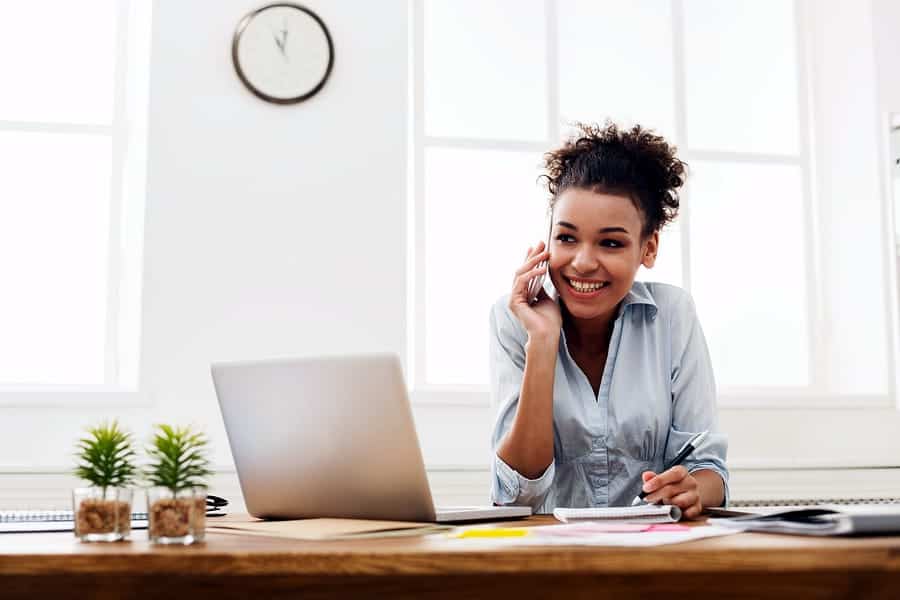 A photo of a woman talking on the phone in her office.