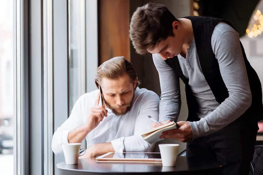 A photo of two men having a quick discussion about their mobile app design.