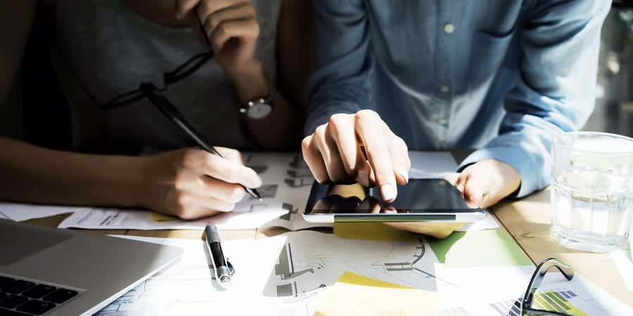 A photo of two coworkers looking at something on a tablet.