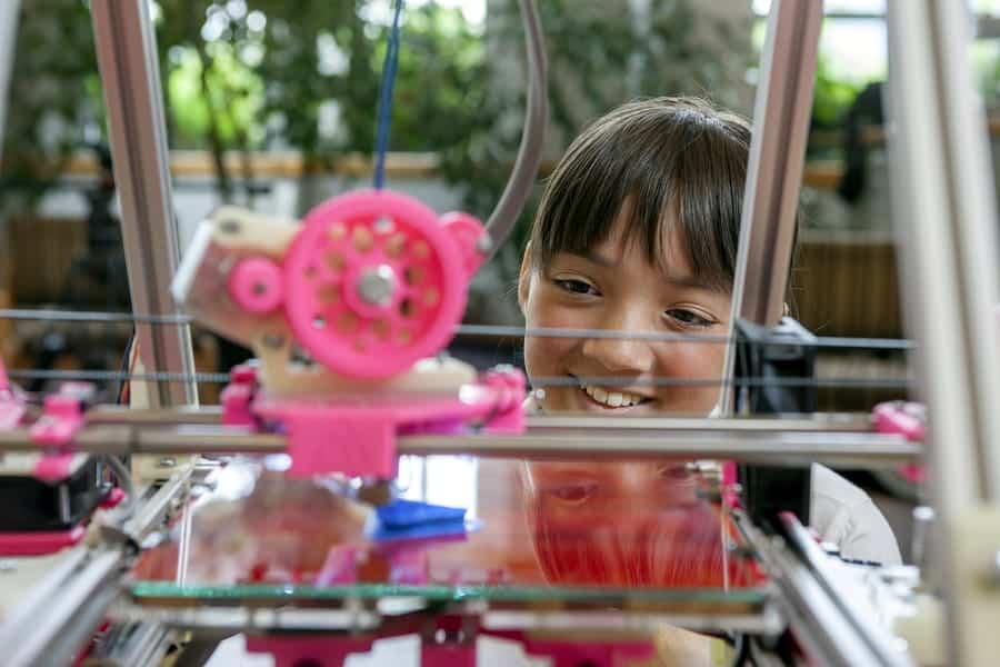 A photo of a young girl watching a 3D printer.