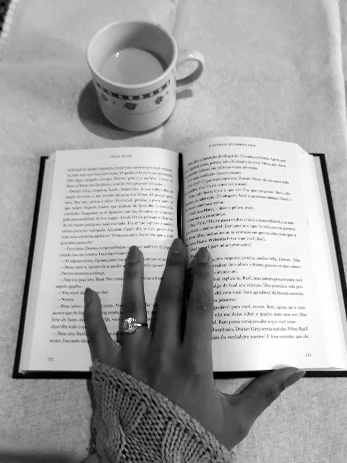 A black and white photo of a woman’s hand resting on an open book.
