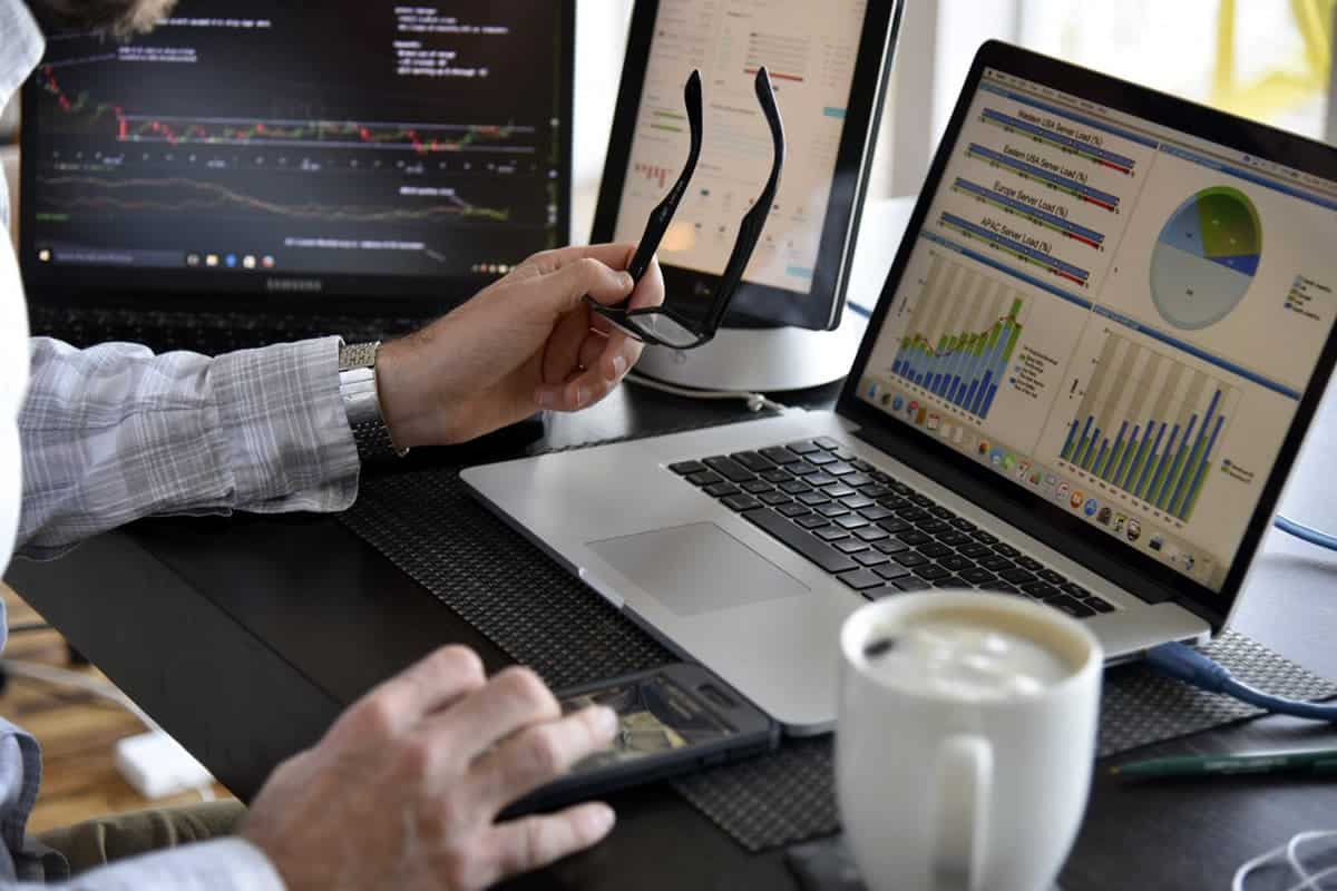 A photo of a man sitting at a desk with multiple computer screens in front of him.