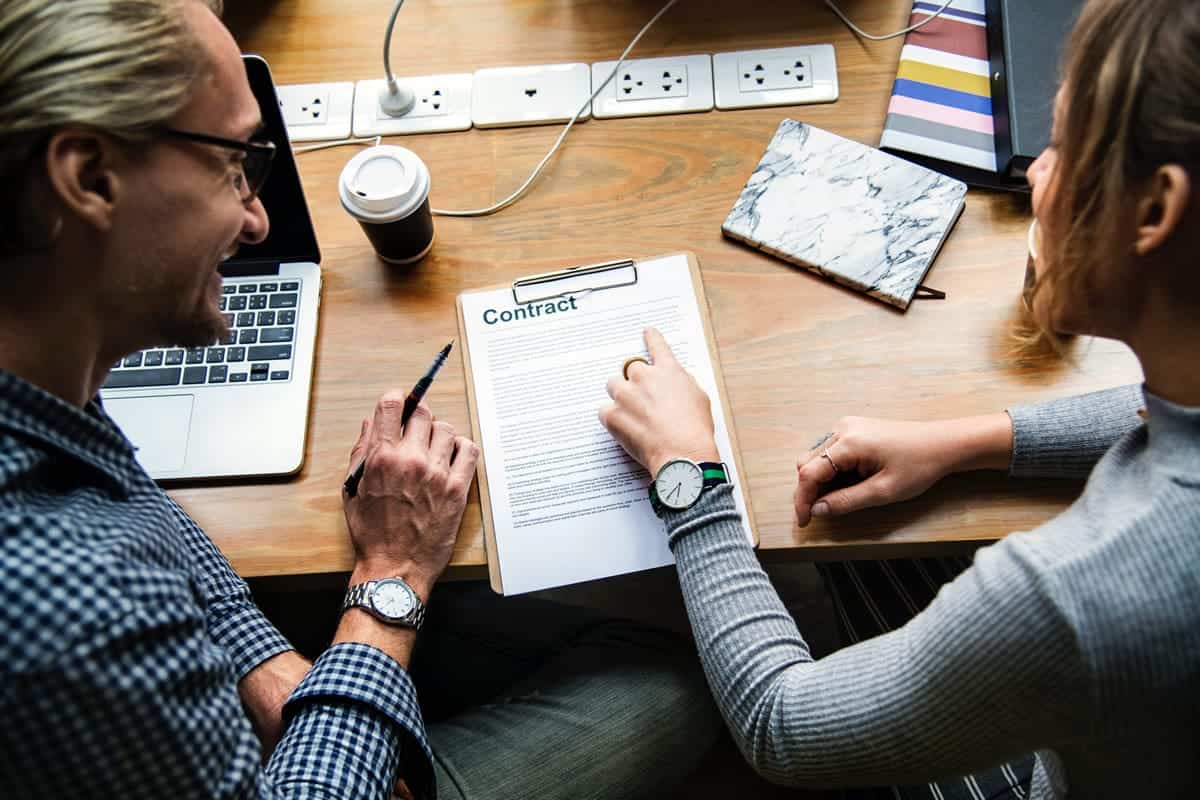 A man and woman meeting at a desk, discussing a contract.