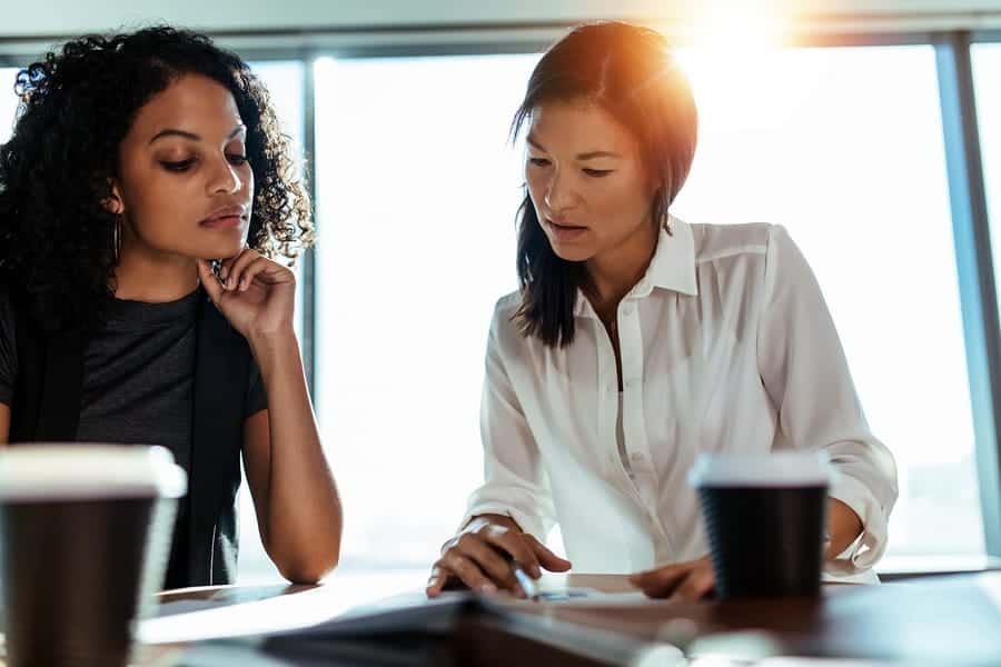 A photo of two women looking at paperwork during a meeting.