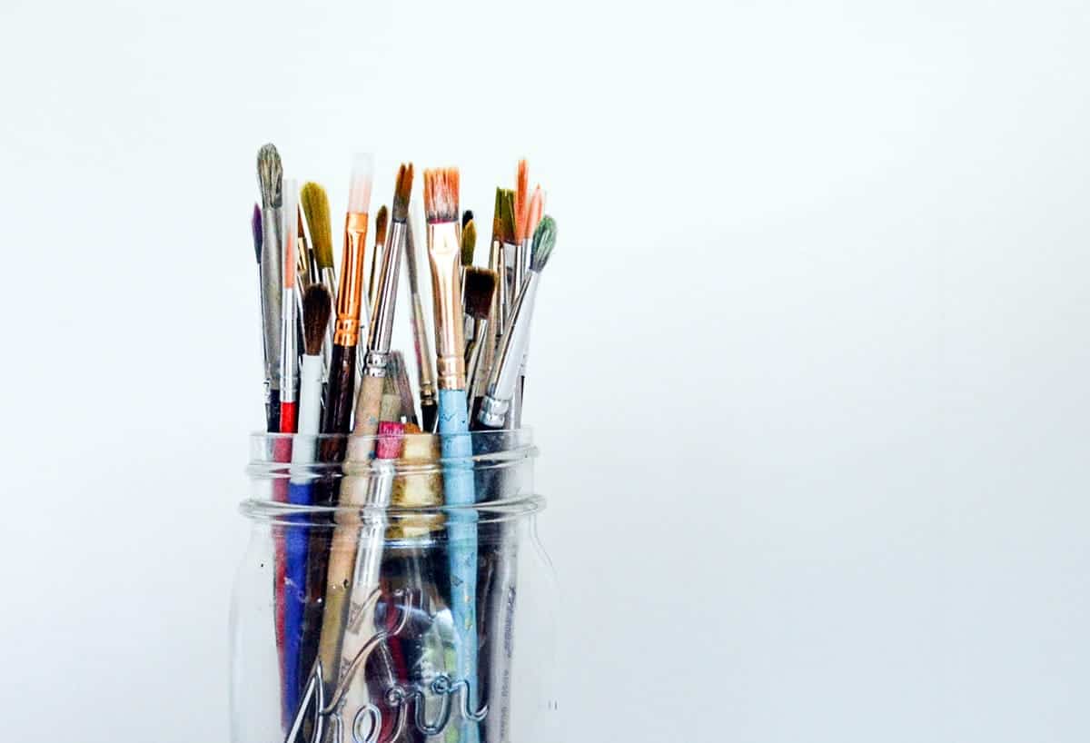 Several paintbrushes in a glass jar.