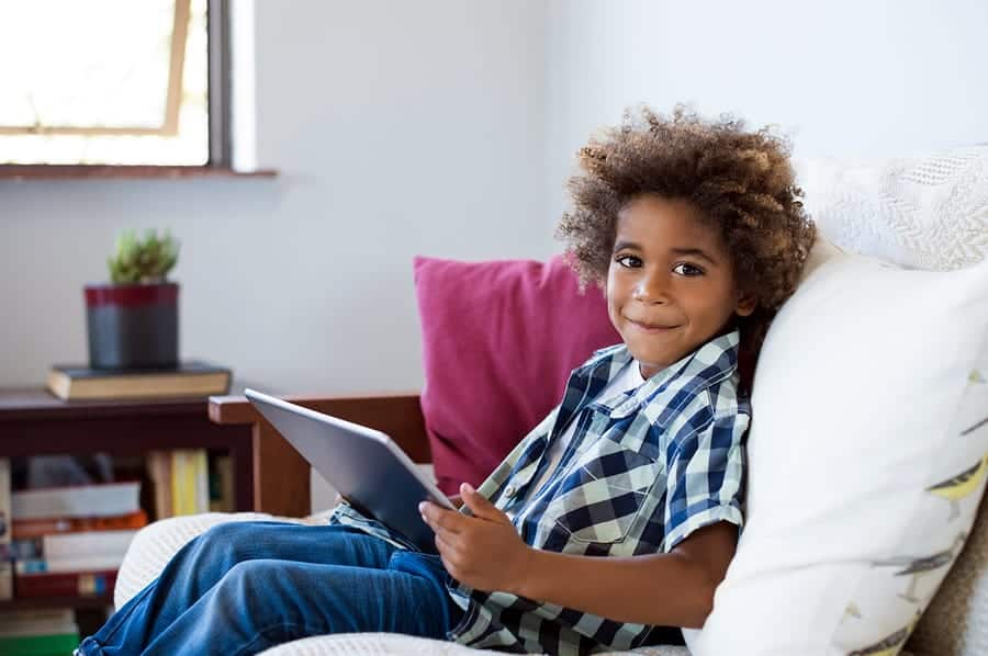 A photo of a happy young child holding a tablet in his hands.