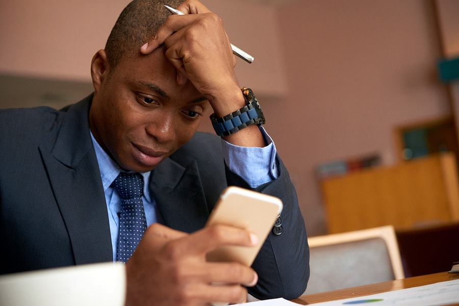 A photo of a man in a suit checking messages on his phone in between meetings.