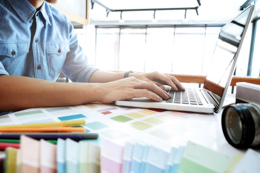 A photo of a mobile app designer surrounded by color swatches at his desk.