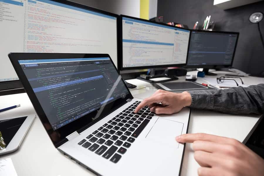 A photo of a mobile app developer’s desk, complete with a laptop and four extra computer monitors.