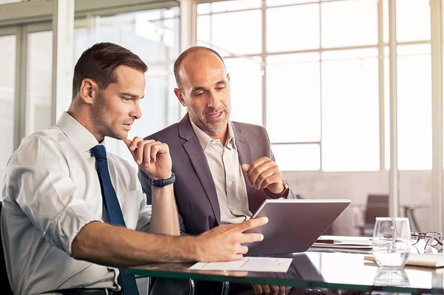 A photo of two men looking at a tablet in their office.