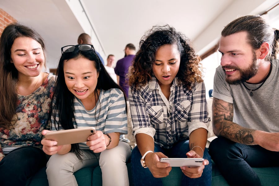 A photo of two teenagers testing out a mobile app prototype while the designers observe.