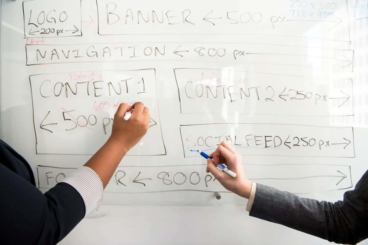 Two coworkers working out a design solution on a whiteboard.