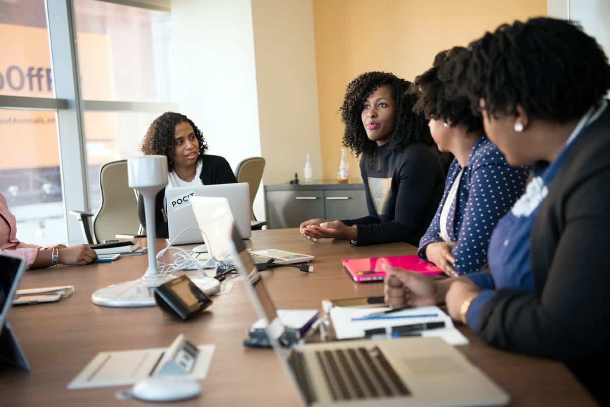 Women in a meeting, sitting around a table.