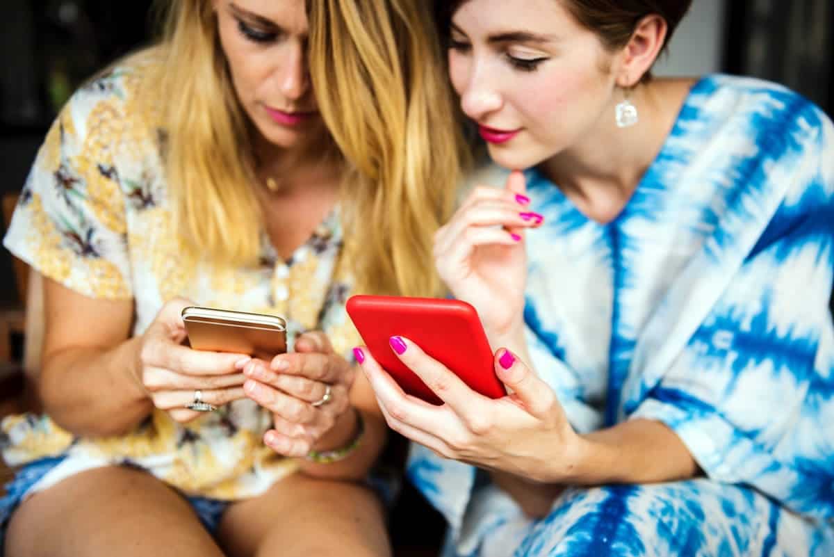 Two women looking at apps on their smartphones.