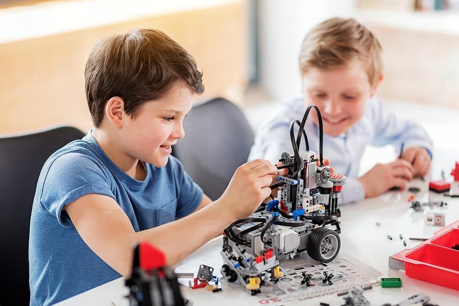 A photo of two children building a vehicle from a kit.