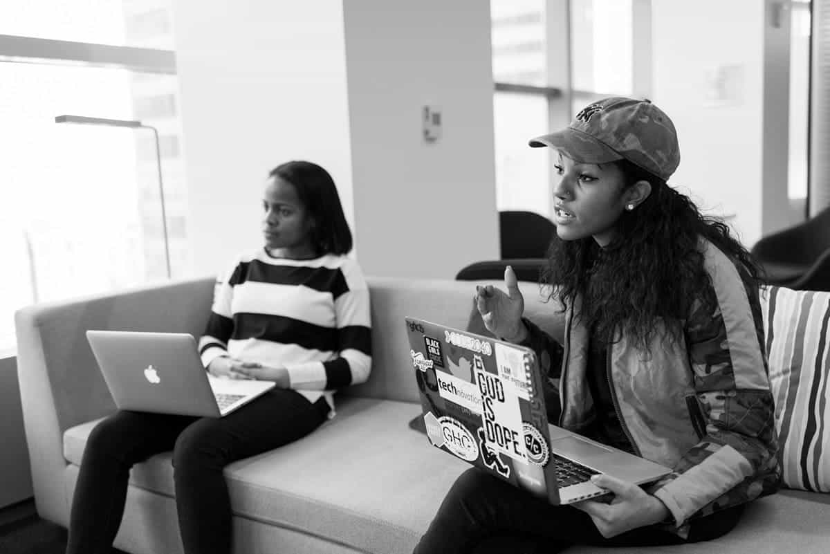 Two coworkers sitting in front of their computers and talking through feedback.