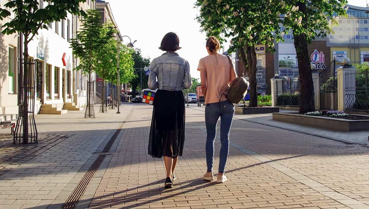 Two women walking down a cobblestone road.
