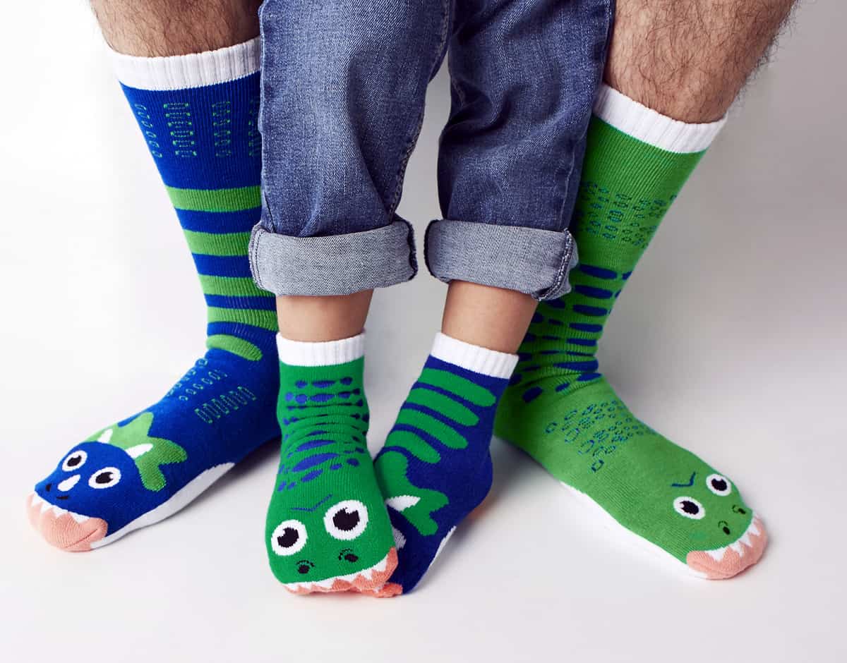 A photo of an adult and a child wearing the T-rex and Triceratops socks from Pals Socks.