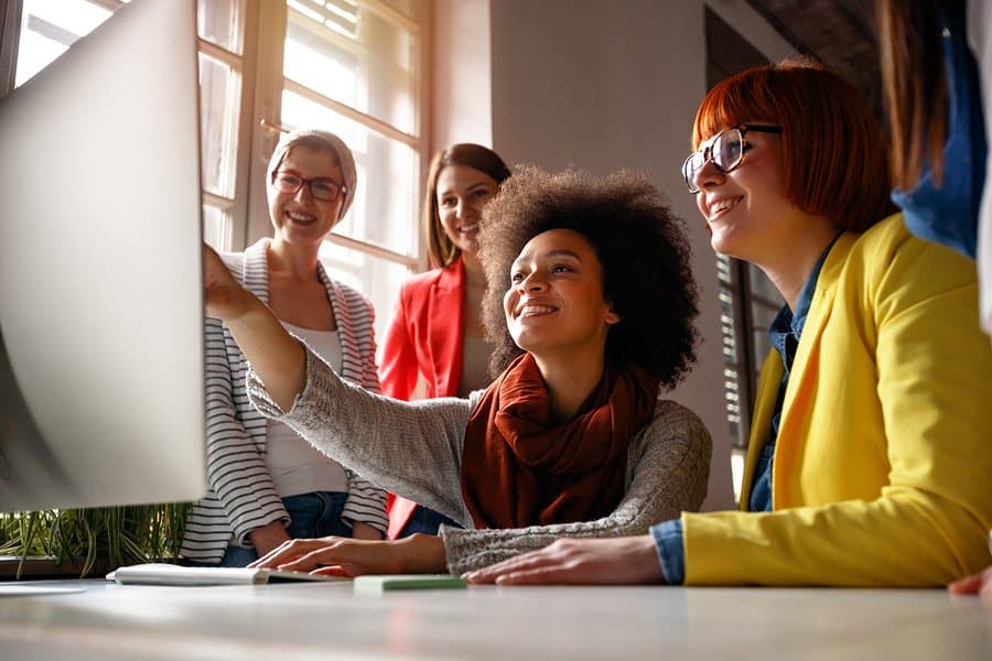 A photo of a mobile app design team checking out the new design ideas on a computer.