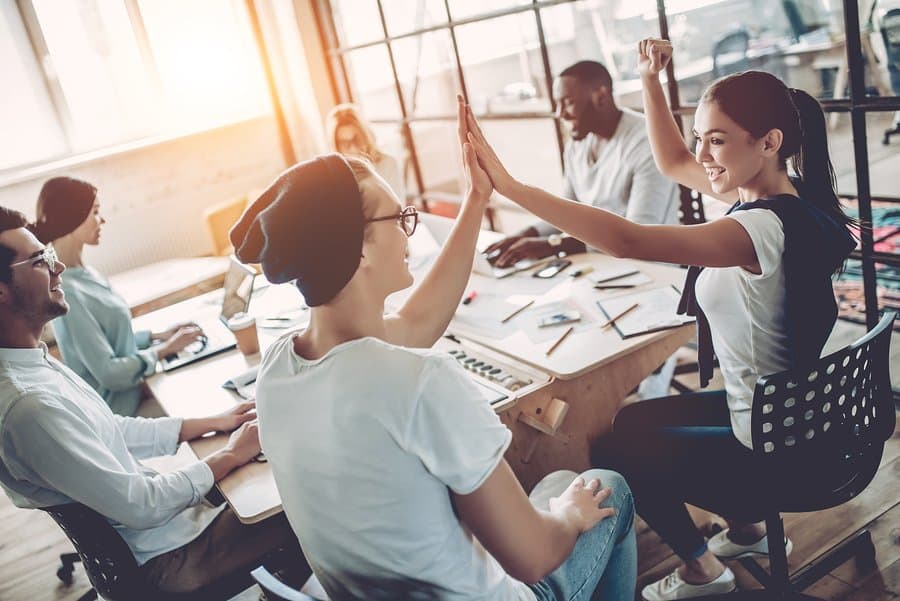 A photo of two teammates high-fiving during a meeting.