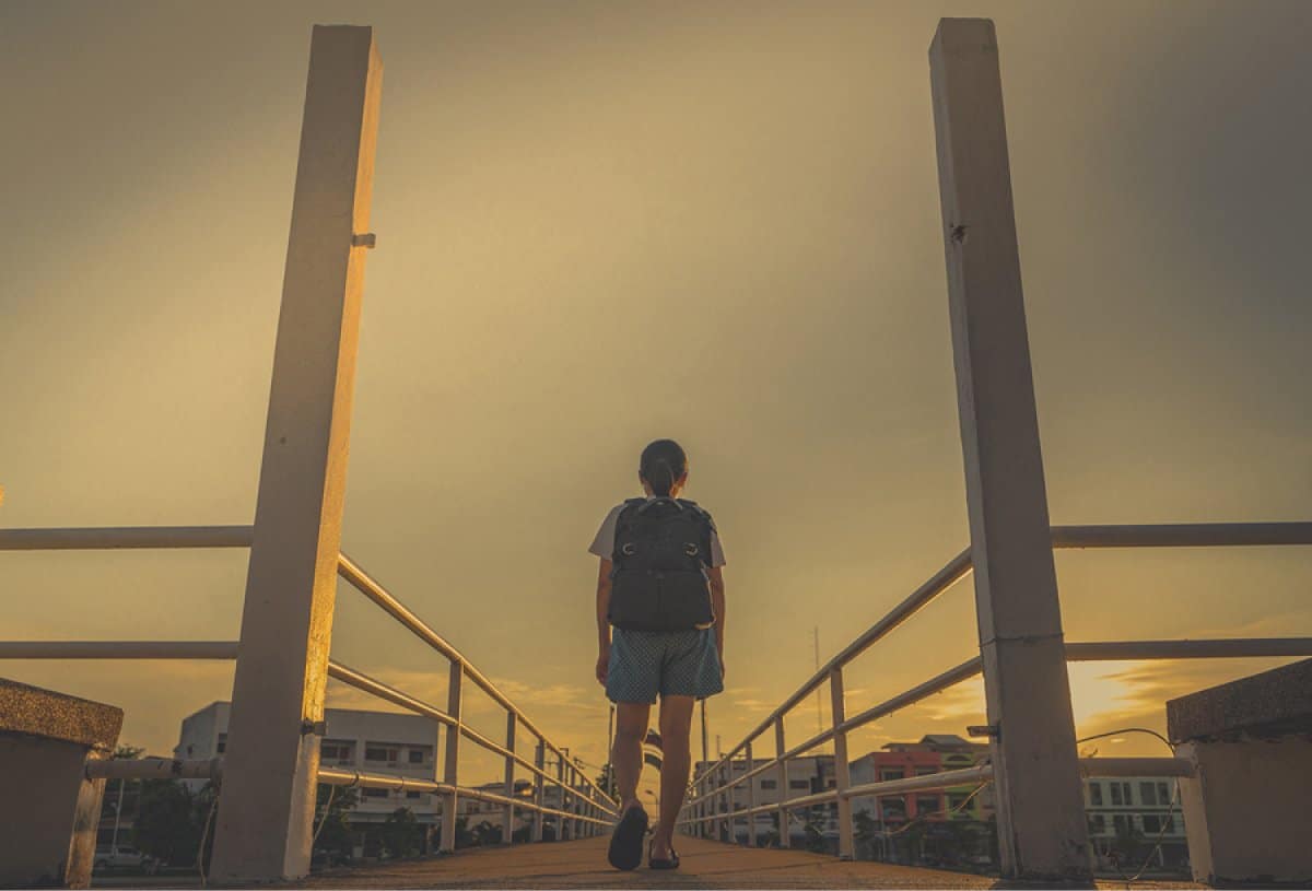 A photo of a woman walking alone on a bridge at dusk.