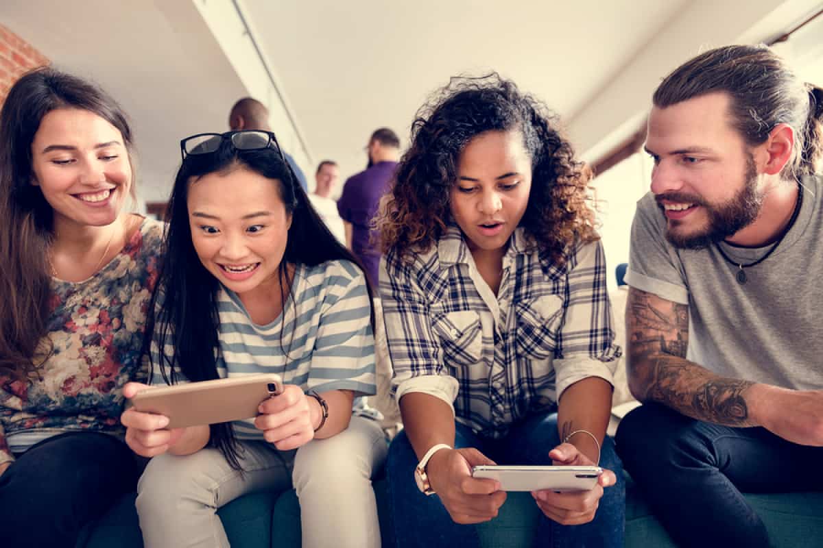 A photo of two teenagers testing a mobile game while the design team observes.