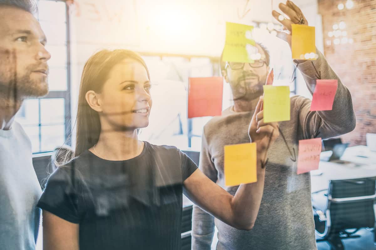 A photo of a mobile app design team gathered around a wall of sticky notes.