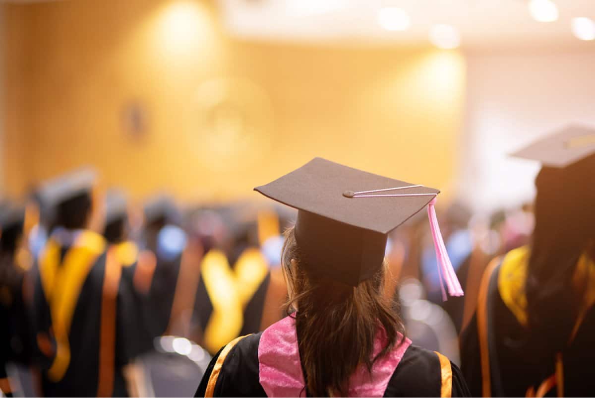 A photo taken from behind a graduate watching a commencement ceremony.