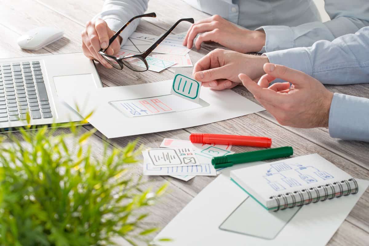 A photo of two mobile app designers using paper cutouts to work through their layout options.