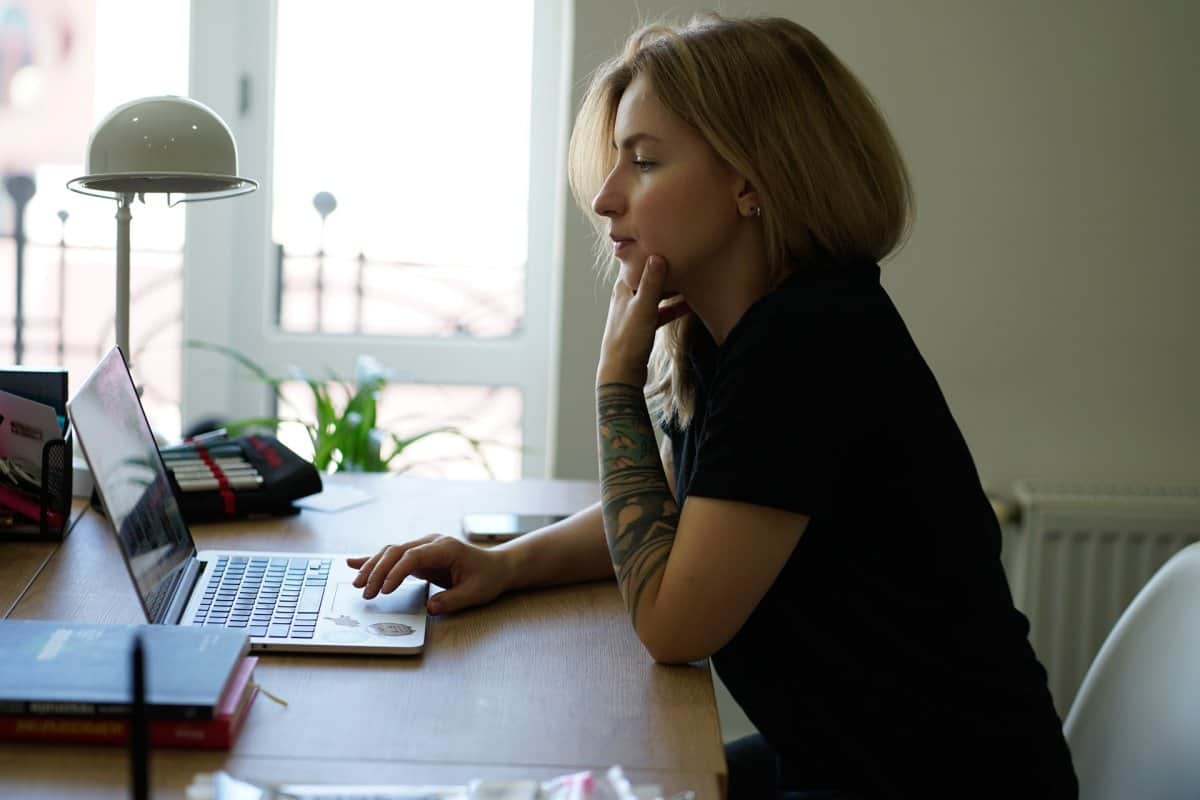 A woman looking at her computer screen with her chin in her hand