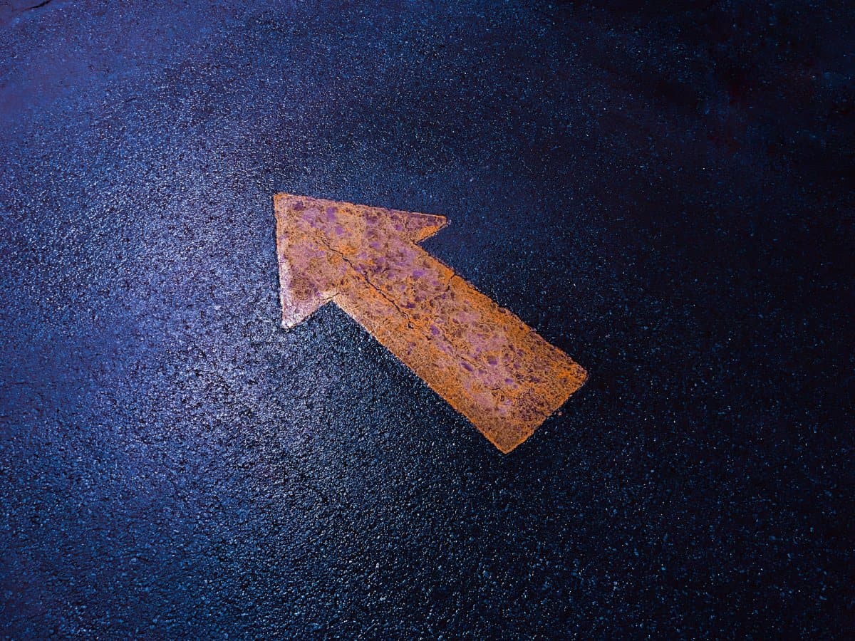 A yellow up arrow painted on a street.