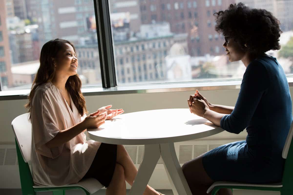 Two women talking about good design at an office overlooking a city.