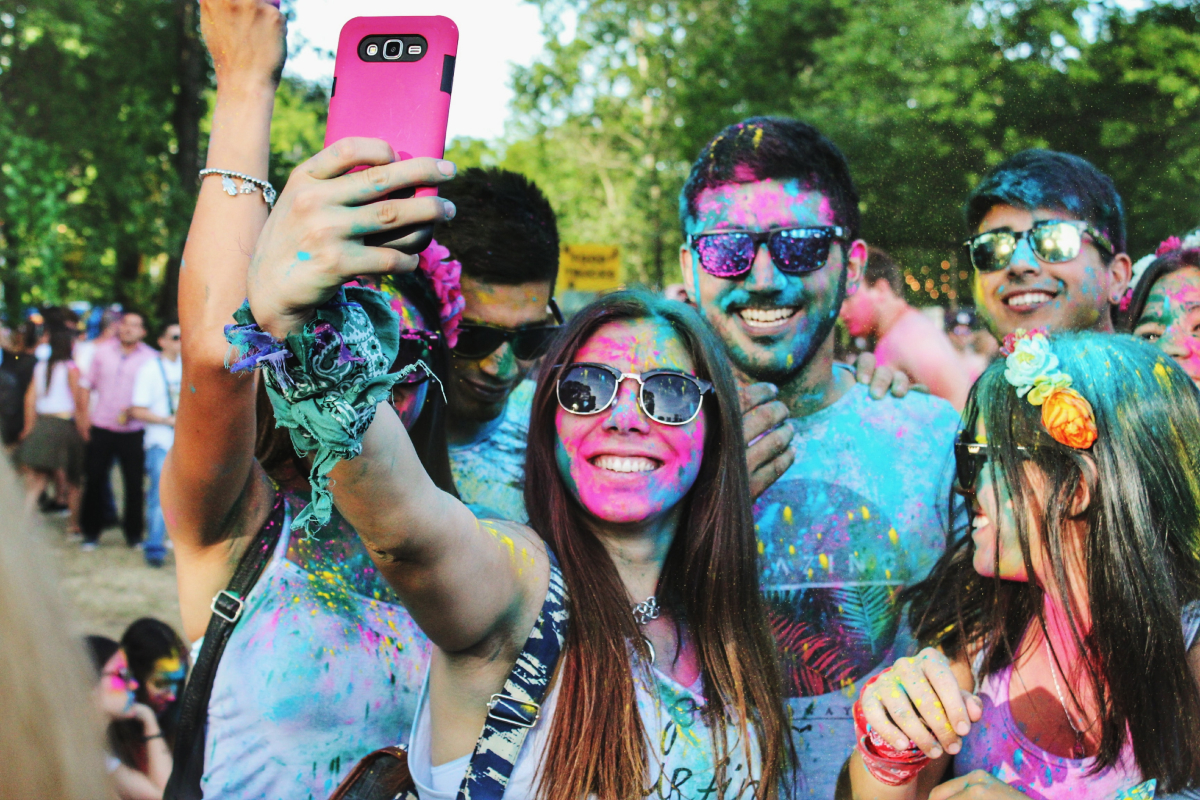 A photo of a young woman taking a selfie of her group of friends after a color run event.