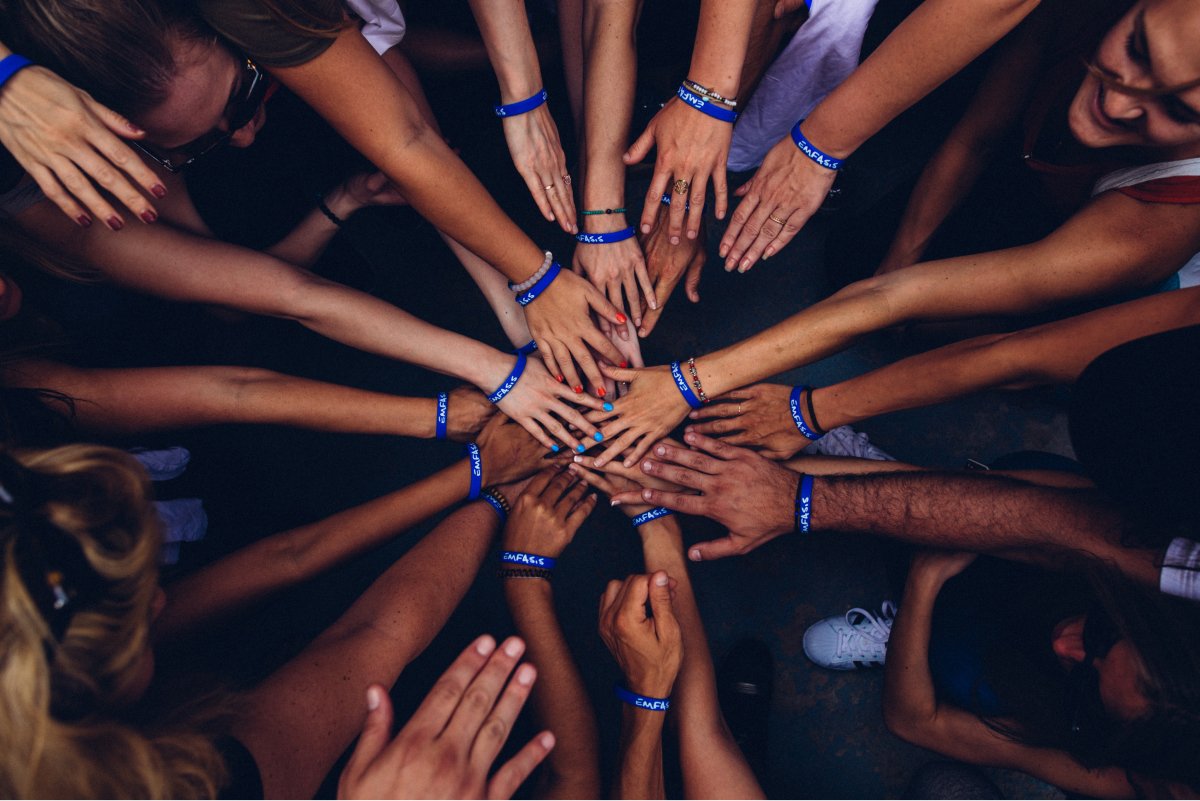 A top-down photo of people’s hands in a circle.