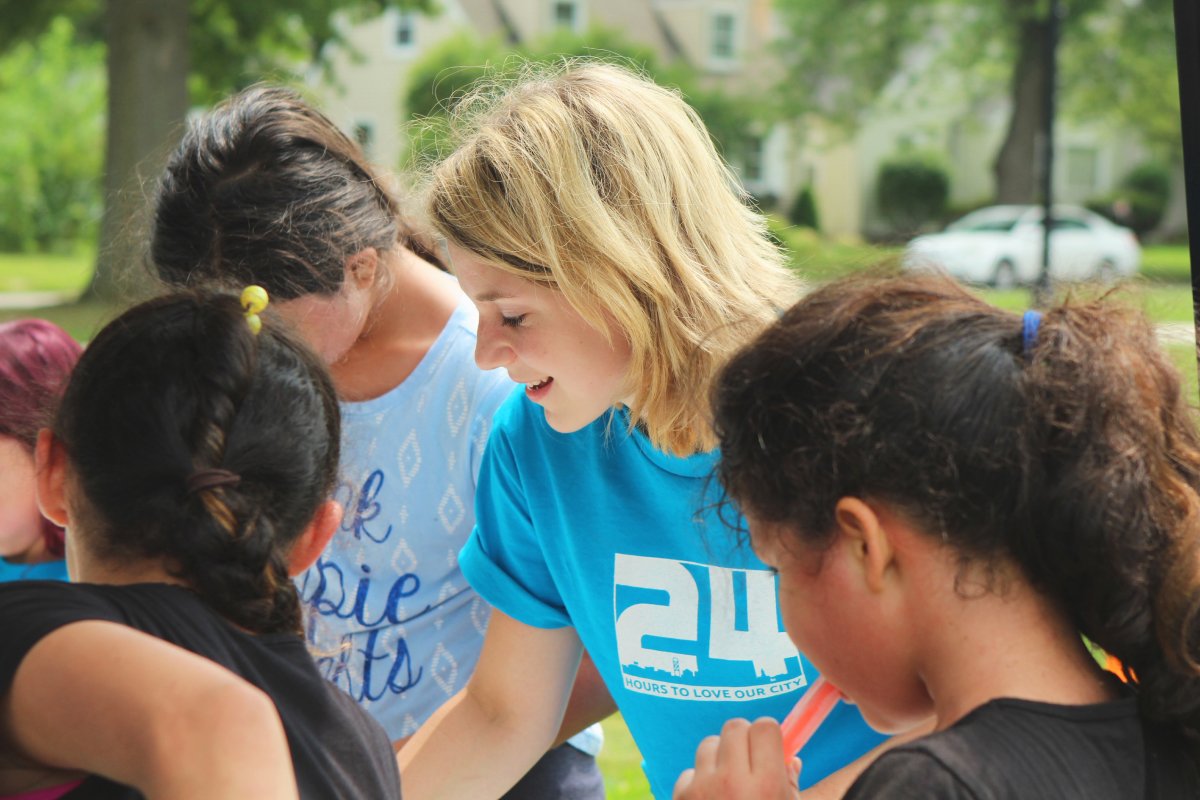 A photo of a woman helping children at a community service event.