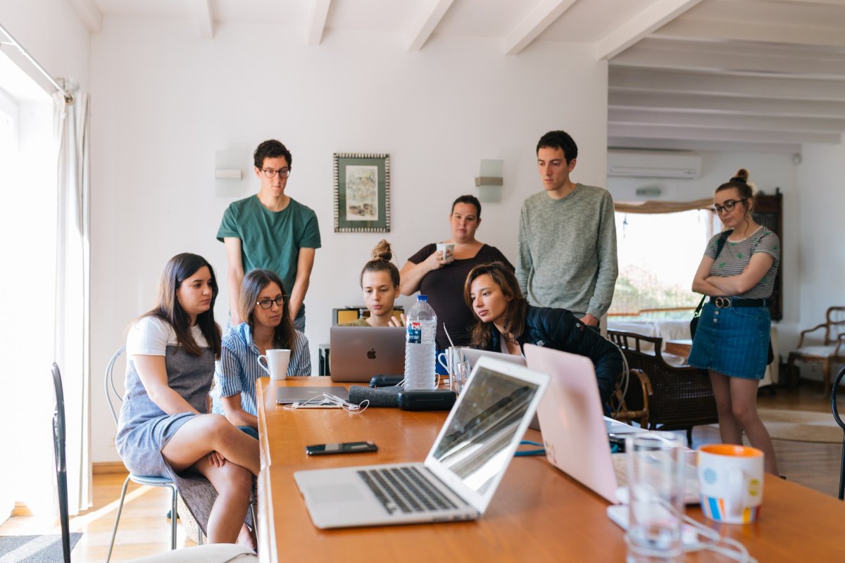 A team huddled around a laptop during a meeting at a cafe.