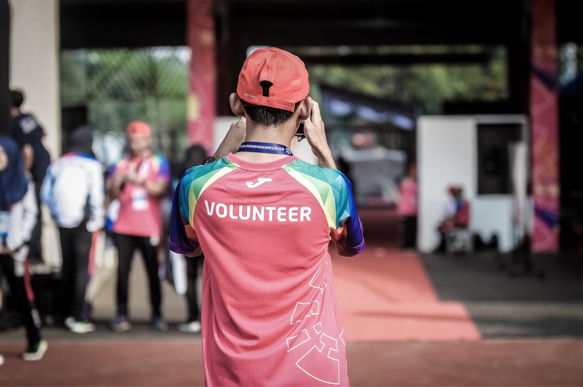 A photo of a person from behind wearing a shirt that says “volunteer.”