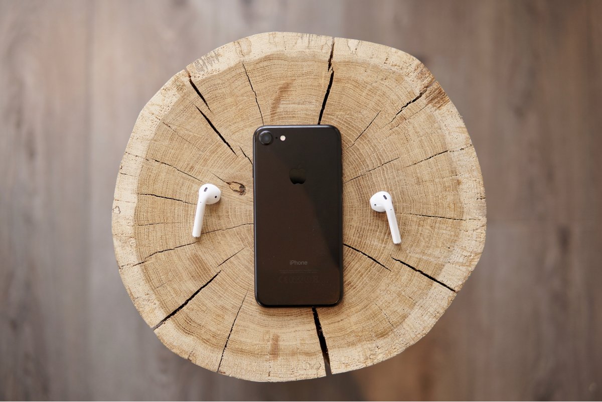 A photo of Apple AirPods sitting next to an iPhone.