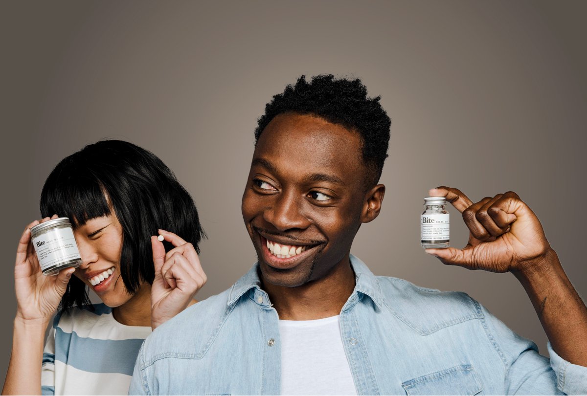 A photo of two people holding bottles of Bite toothpaste bits.