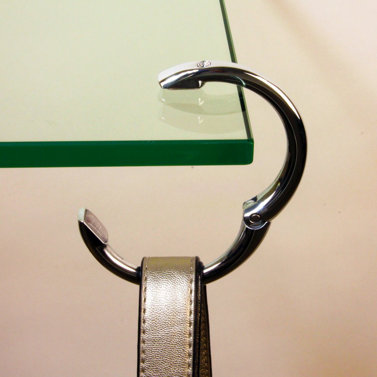 A photo of a Clipa holding up a purse on a glass table.