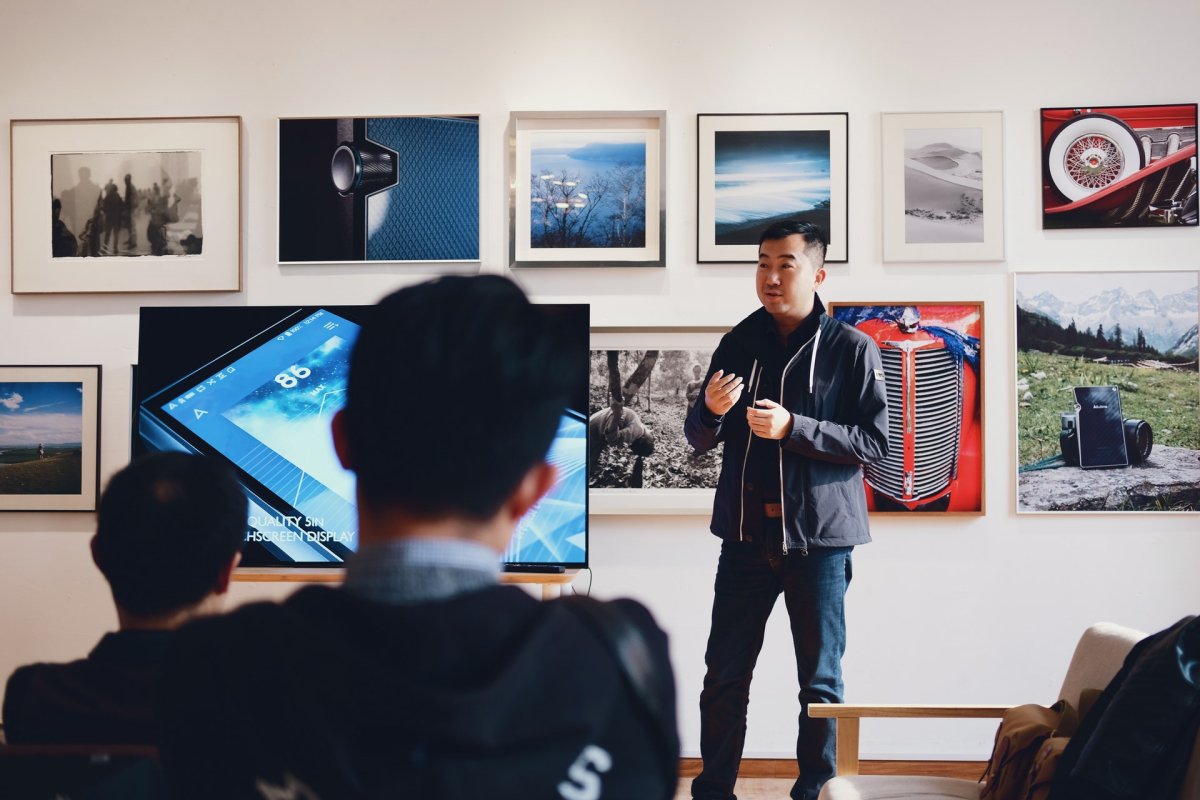 A man giving a lecture in a photography gallery.
