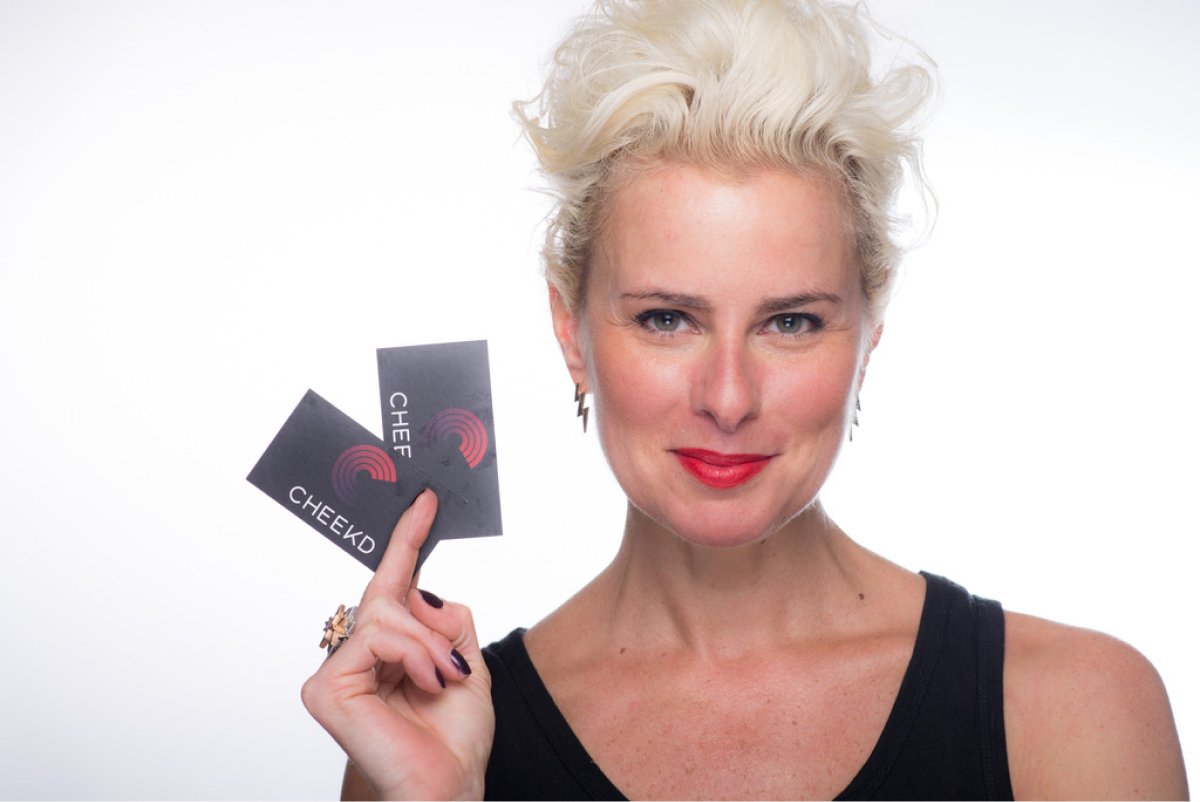 A photo of entrepreneur Lori Cheek holding a couple business cards in her hand.