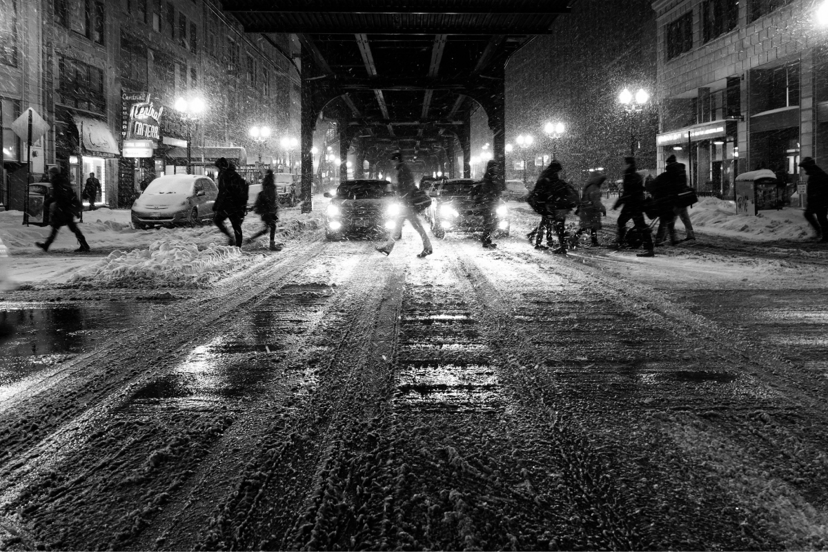 A photo of people crossing a snowy street during the winter time.