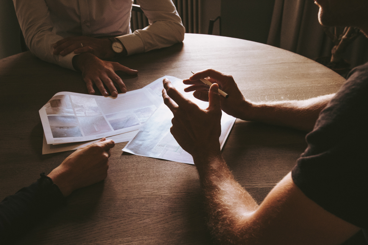 A photo of three people sitting at a table, discussing mockups for a new mobile app.