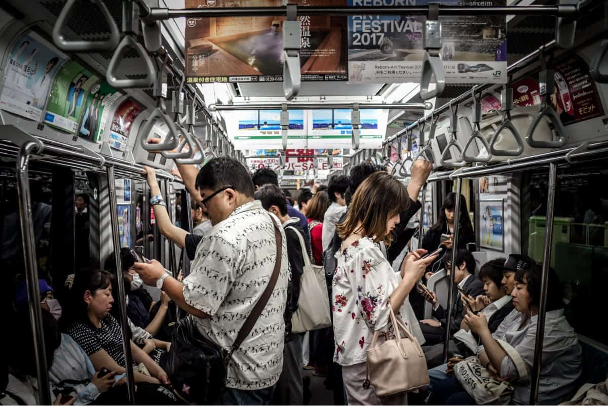 A photo of a subway car full of passengers, most of whom are looking down at their smartphones.
