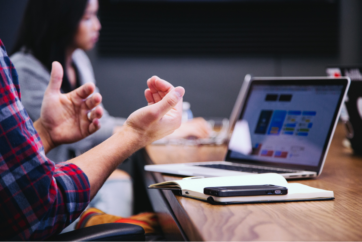 A photo of a person’s hands gesturing while they speak during a team meeting.